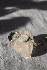 Blue Moonstone sterling silver bracelet shown on textured stone with polished bezel and woven chain detail.