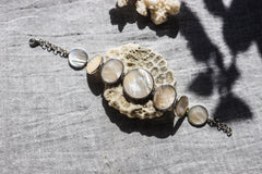 Mother of Pearl sterling silver bracelet shown on textured stone with soft nacre cabochons and polished silver settings.