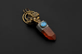 Ganesha Lithium Quartz Aquamarine pendant shown on a dark background with gold-plated brass, oxidized silver, and red Quartz point.