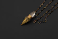 Clear Quartz point pendant shown with warm brass torch setting and handmade surface texture.