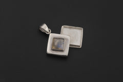 Diamond-shaped Labradorite locket pendant displayed on dark background with polished silver finish.