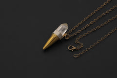 Clear Quartz brass torch talisman displayed on dark background with adjustable necklace chain.