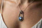 Moonstone pendant in polished 925 sterling silver with celestial ray details, shown worn on a black woven cotton cord.