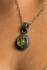 Close-up of natural Peridot in an oxidized sterling silver claw pendant with dark textured silver frame.