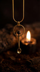 Mount Agung volcanic stone brass ritual spoon shown worn as a pendant near candlelight.