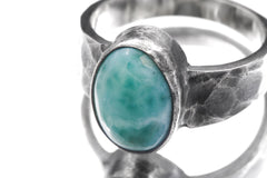 Close-up of AAA Larimar oval cabochon ring showing soft aqua patterning, thick bezel, and hammered silver texture.