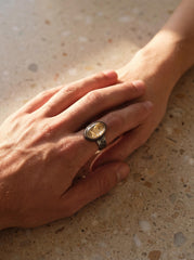 Gold Rutilated Clear Quartz men’s ring in oxidized 925 sterling silver shown worn on the hand with hammered silver band.