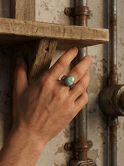 AAA Larimar ring shown worn against rustic wood, with oval aqua cabochon and oxidized hammered sterling silver.