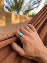 AAA Larimar men’s ring in oxidized 925 sterling silver shown worn on the hand with rugged hammered band.