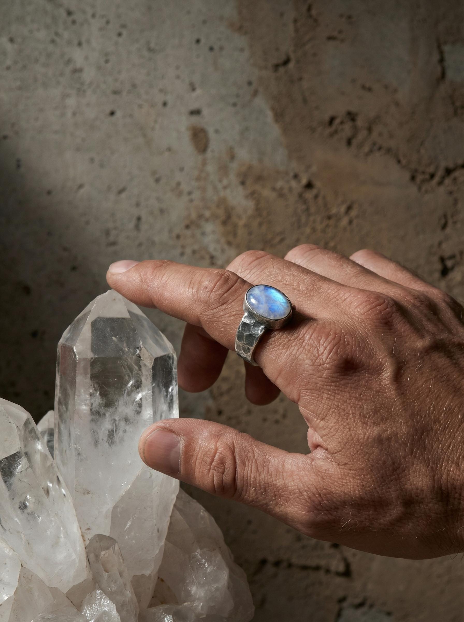 AAA Blue Moonstone men’s ring in oxidized 925 sterling silver shown worn on the hand with rugged hammered band.