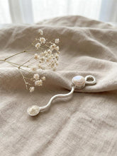 South Sea Pearl sterling silver wavy spoon pendant shown on linen with tiny functional spoon shape and Pearl detail.