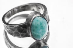 Close-up of AAA Larimar oval cabochon ring showing soft aqua patterning, thick bezel, and hammered silver texture.