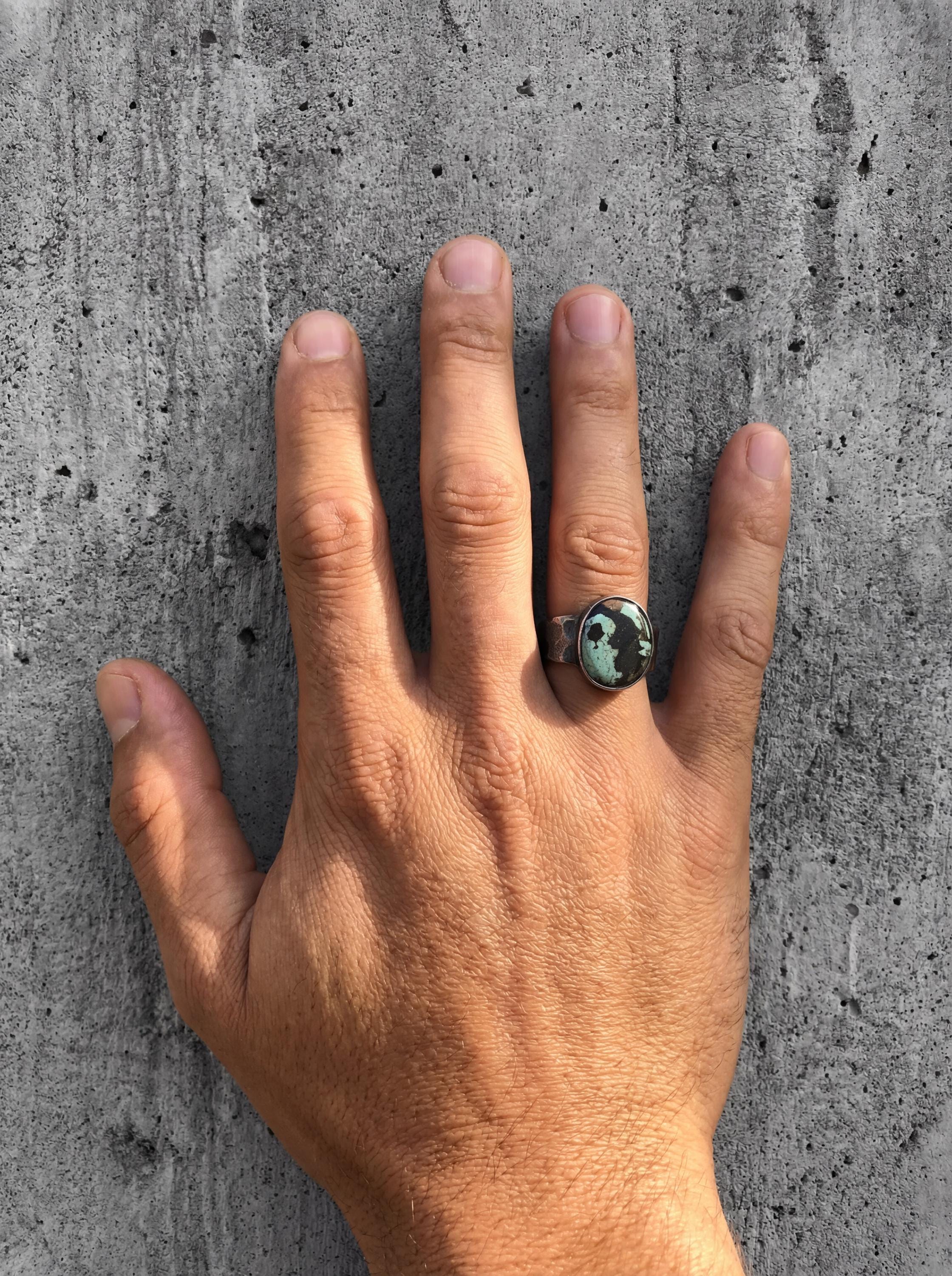 Old World Tibetan Turquoise men’s ring in oxidized 925 sterling silver shown worn on the hand with hammered texture.