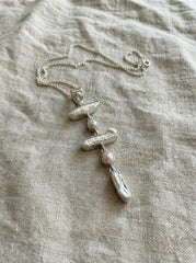 Blue Moonstone and Pearl cascade pendant displayed on linen, with high-shine sterling silver and flowing vertical dangle design.