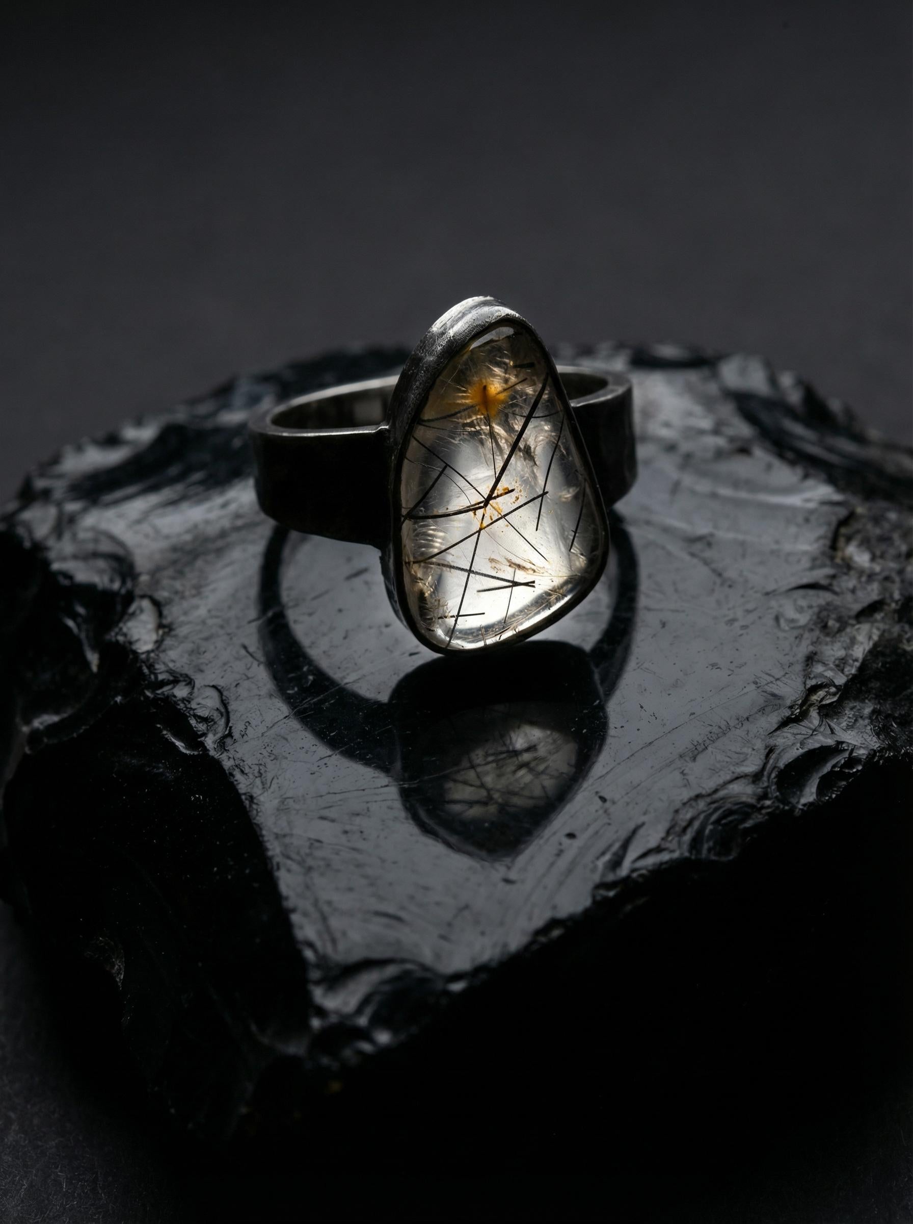 Black Rutile Quartz sterling silver ring displayed on dark stone with hammered oxidized silver band.