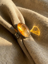 Gold Rutilated Quartz sterling silver ring displayed on fabric with warm golden inclusions and hammered band.