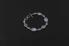 Rainbow Moonstone bracelet displayed on dark background with toggle clasp and polished sterling silver links.