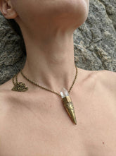 Clear Quartz torch pendant shown worn on model with brass setting and crystal point.