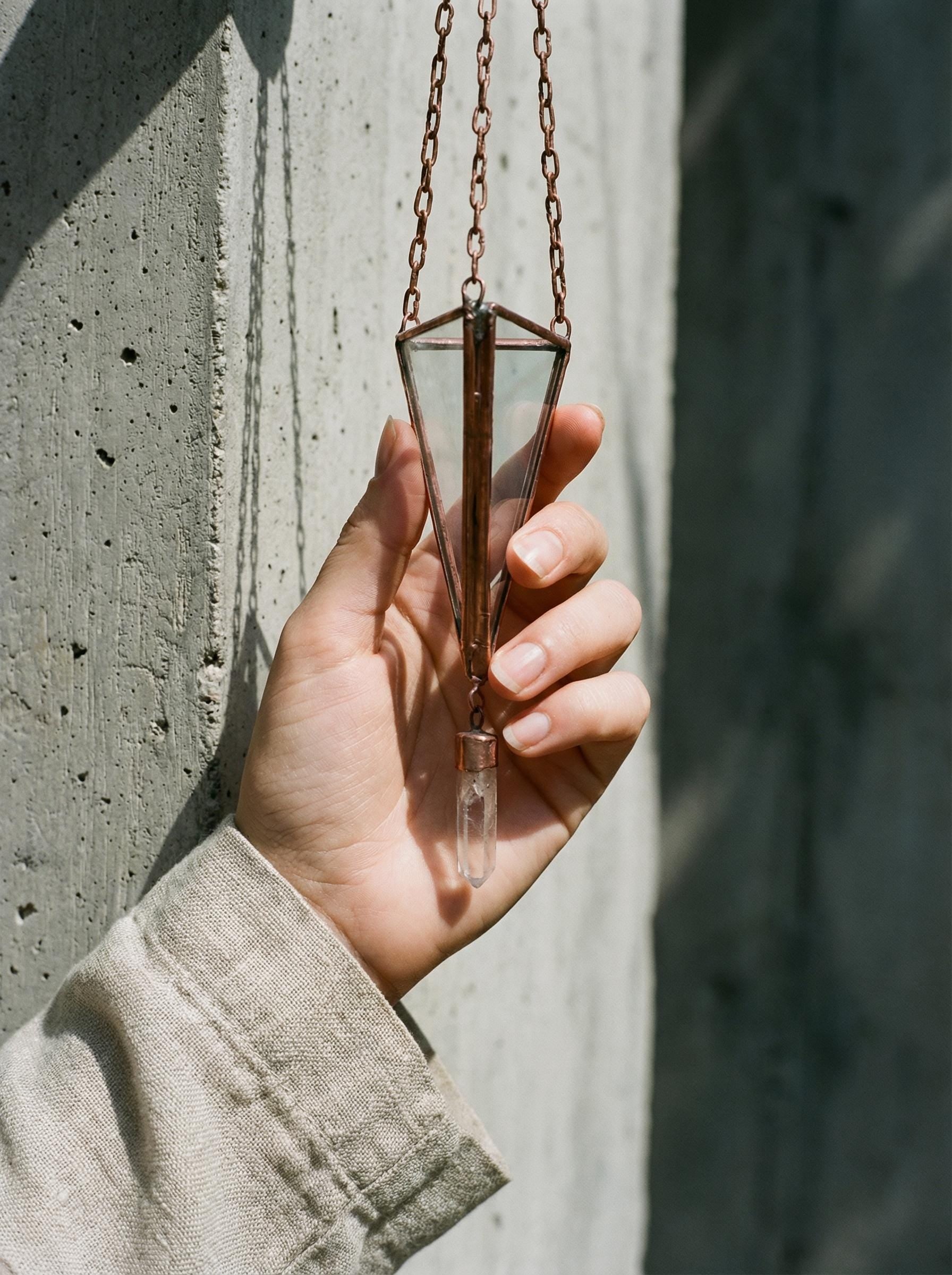 Copper Triangle Quartz hanging decoration shown in hand with glass prism frame, hanging chain, and raw Clear Quartz point.