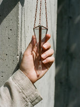 Copper Triangle Quartz hanging decoration shown in hand with glass prism frame, hanging chain, and raw Clear Quartz point.