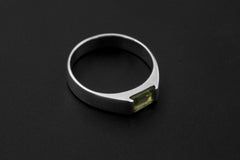 Peridot ring shown worn on hand with clean polished sterling silver band and green gemstone.