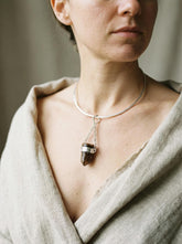 Bullet Brown Tourmaline Dravite Pendant shown worn on the chest with sterling silver frame and black cotton necklace.
