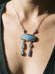 Boulder Opal and Moonstone necklace shown worn on the chest, with sterling silver wire link chain and celestial dangle design.