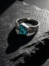 Blue Apatite Textured Silver Ring shown on dark rock with semi rough blue crystal and handmade sterling silver band.