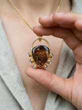Golden Earth and Moonlight pendant held in hand, with Brown Dravite Tourmaline, Blue Moonstone accents, and gold-plated silver.