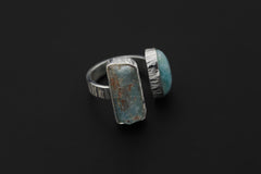 Tidal Union Aquamarine and Larimar ring on a dark background, showing the open silver band and opposing stone settings.