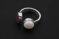 Dual Stone Balance ring on a dark background, showing Ruby and South Sea Pearl in an adjustable sterling silver open band.