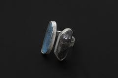 Tide and Shadow Smoky Quartz and Aquamarine Ring shown on black background with blue-green Aquamarine and dark crystal.