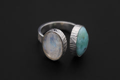Dual Stone Ocean Light ring on a dark background, showing Larimar and Blue Moonstone in an adjustable silver band.