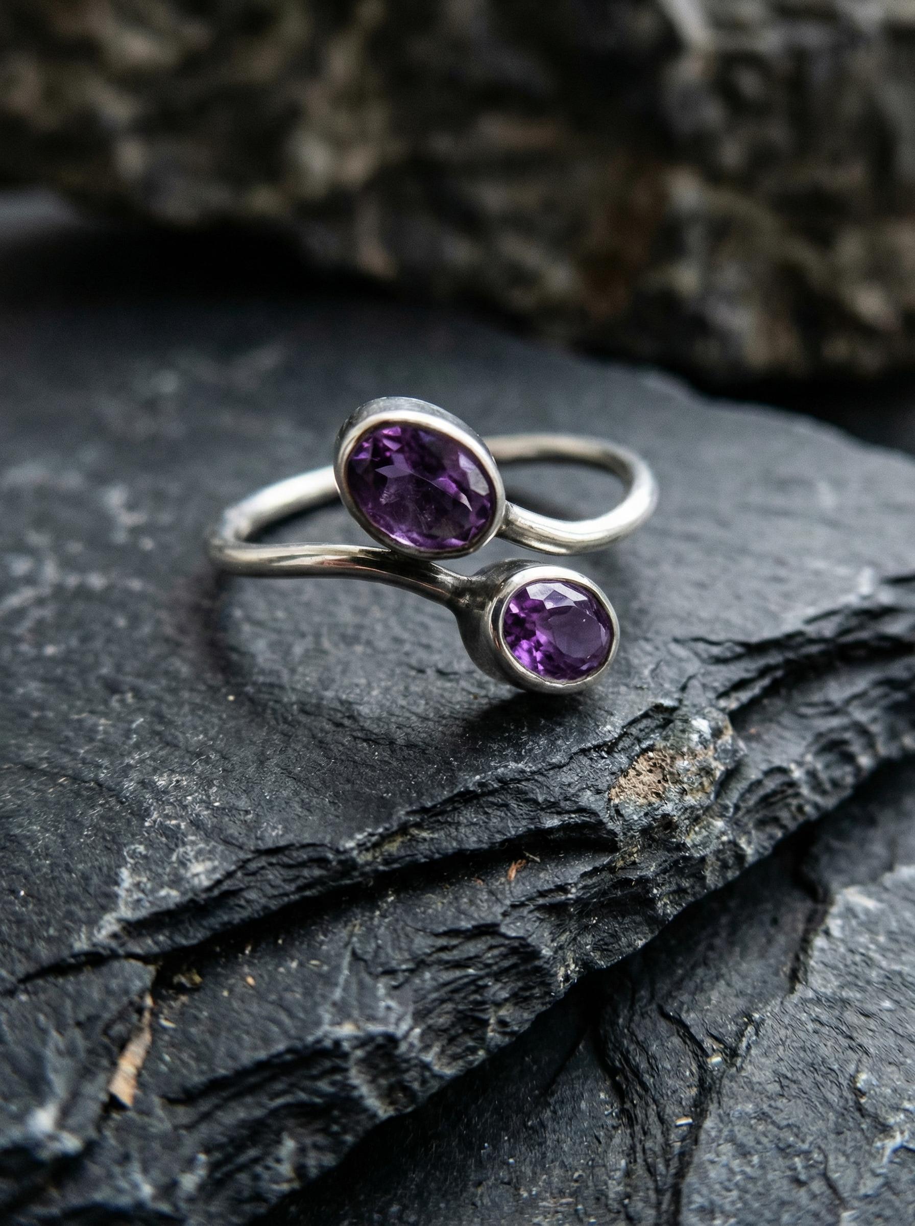 Twin Amethyst open ring displayed on dark slate with polished sterling silver and violet gemstones.
