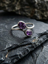 Twin Amethyst open ring displayed on dark slate with polished sterling silver and violet gemstones.
