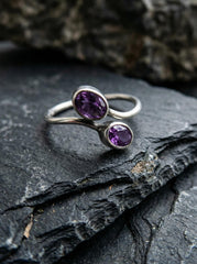 Twin Amethyst open ring displayed on dark slate with polished sterling silver and violet gemstones.