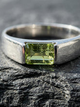 Peridot sterling silver ring shown on stone with polished band and octagon green gemstone.