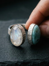 Larimar Blue Moonstone adjustable ring in high-shine 925 sterling silver shown held on a dark textured background.