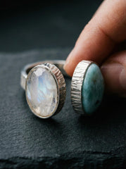 Larimar Blue Moonstone adjustable ring in high-shine 925 sterling silver shown held on a dark textured background.