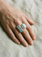 Adjustable Aquamarine Larimar ring in high-shine 925 sterling silver shown worn on the hand with two blue stones.