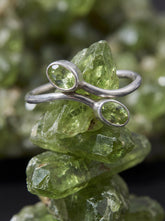 Dual Peridot open ring shown on green crystal with polished sterling silver and olive green stones.