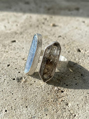Tide and Shadow Smoky Quartz and Aquamarine Ring shown on stone with raw crystal contrast and polished silver band.