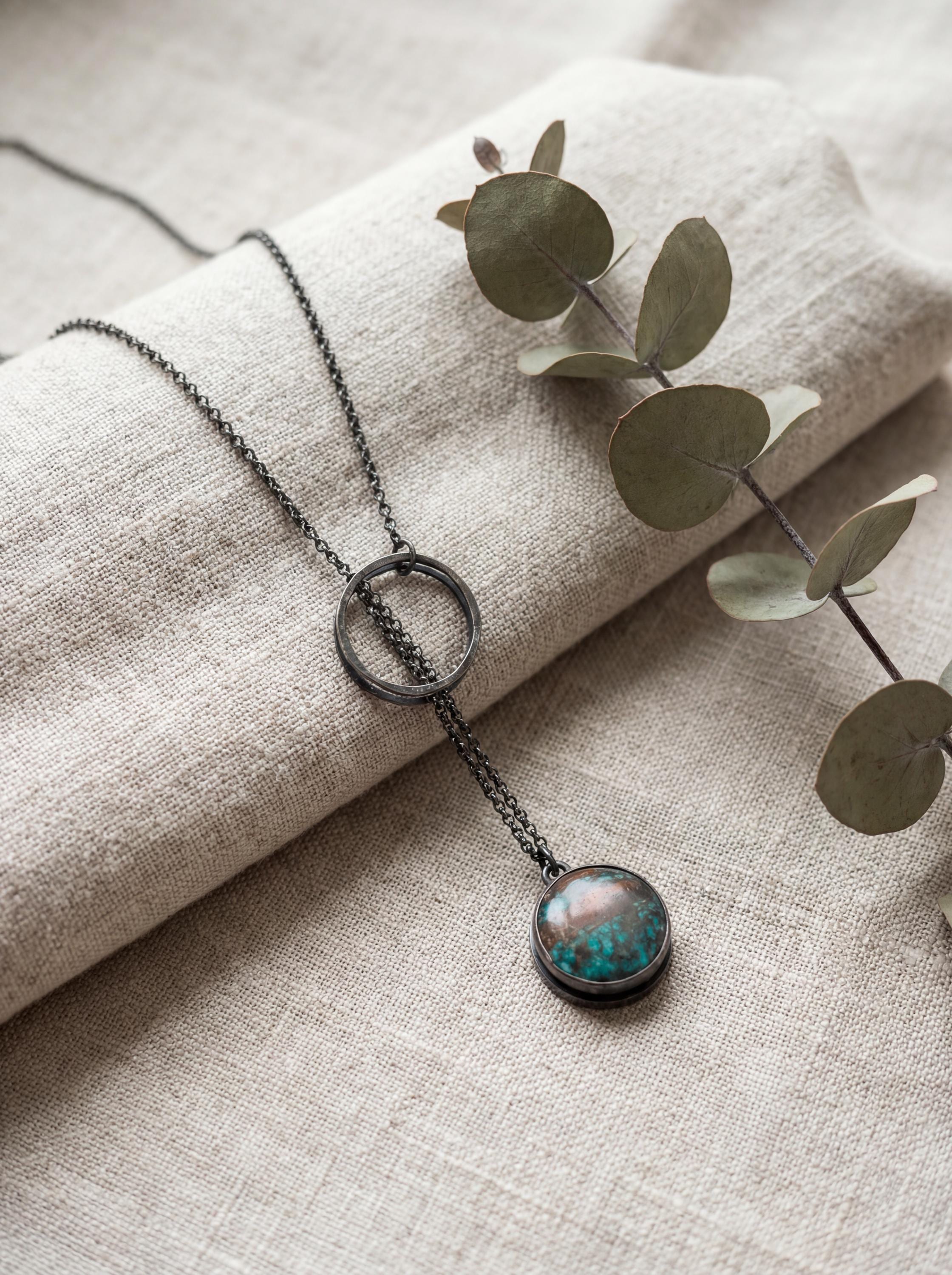 Turquoise lariat necklace displayed on linen with oxidized sterling silver chain and adjustable loop closure.