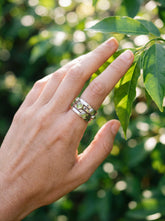 Five Stone Peridot Orbit Ring shown worn on hand with polished sterling silver and green cabochons.