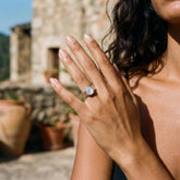 Radiant Blue Moonstone Hammered Ring shown worn on hand with shiny sterling silver band and round pale blue gemstone.