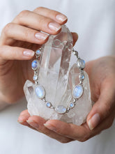 Rainbow Moonstone sterling silver bracelet shown worn on the wrist with soft blue flash and polished silver settings.