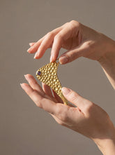 Gold-plated Amethyst ritual spoon pendant held in hand with organic bubble texture and sculptural form.