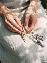 Gold-plated Double Garnet ritual spoon pendant shown worn as a long sculptural talisman necklace.