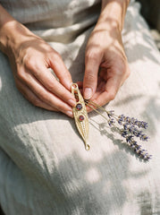 Gold-plated Double Garnet ritual spoon pendant shown worn as a long sculptural talisman necklace.