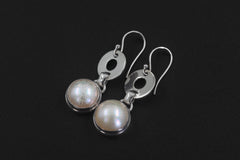 Pearl sterling silver earrings displayed on dark background with circular silver links and luminous round drops.